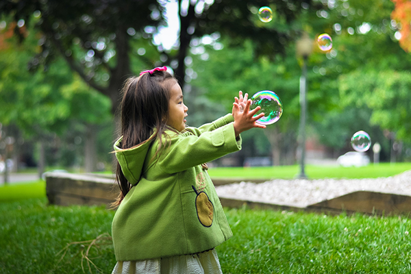 Child playing with blown bubble
